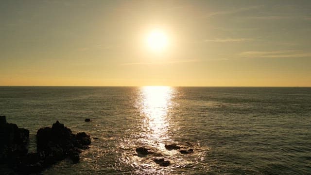 Sunset over a calm ocean with rocks