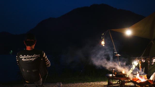 Person enjoying camping by a fire at night