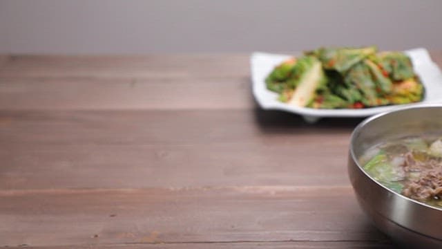 Clear Yukgaejang with pickled vegetables, rice, and green onions on the table