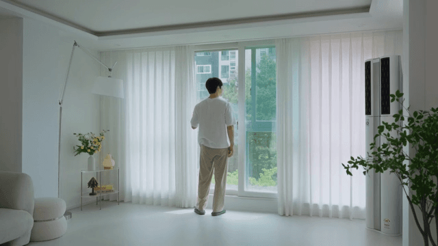 Man looking out a window in a bright living room