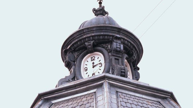 Superstructure of a tall clock tower under a cloudy sky