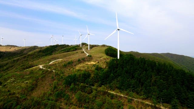 Wind turbines on a lush mountain ridge during daytime