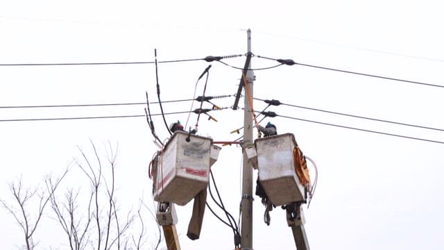 Workers repairing electrical lines on utility pole