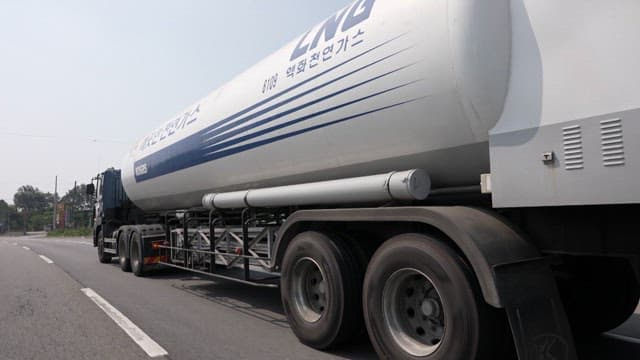 A liquid natural gas tanker driving on a highway.