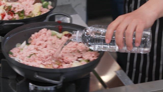Adding Water to a Pan of Cooking Ingredients