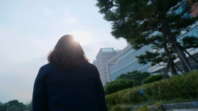 Back view of a woman walking down a street with tall buildings in view