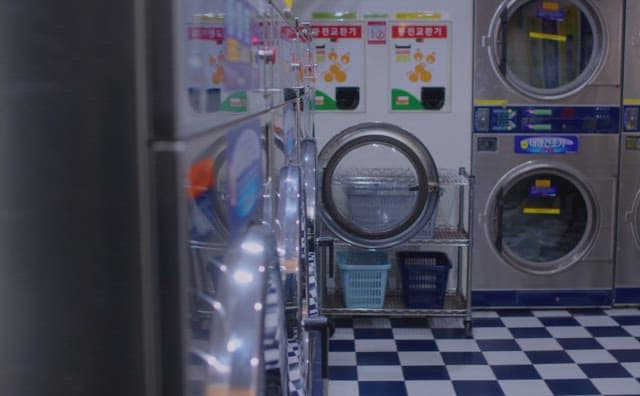Two women sitting in a laundromat, blowing bubbles