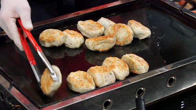 Fried dumplings being cooked and served