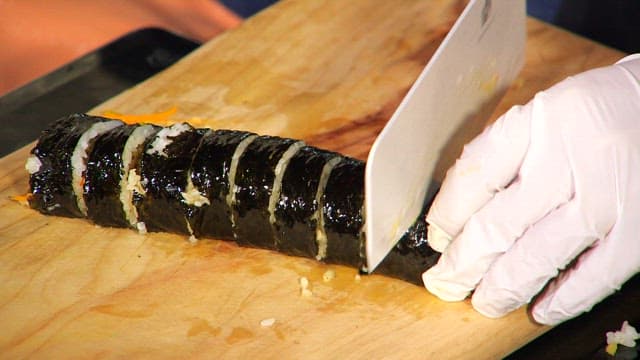 Slicing kimbap on a wooden board
