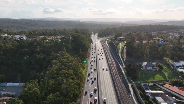 Cars running on a highway surrounded by green space