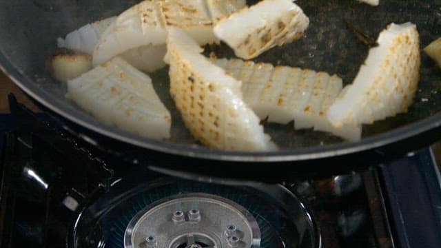 Squid being grilled with garlic in a pan