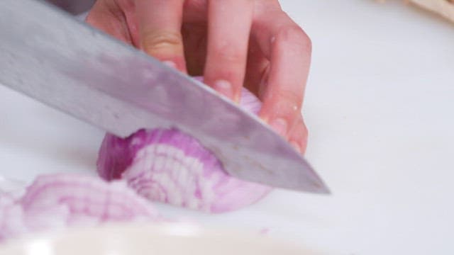 Slicing a Red Onion on a White Cutting Board in a Kitchen