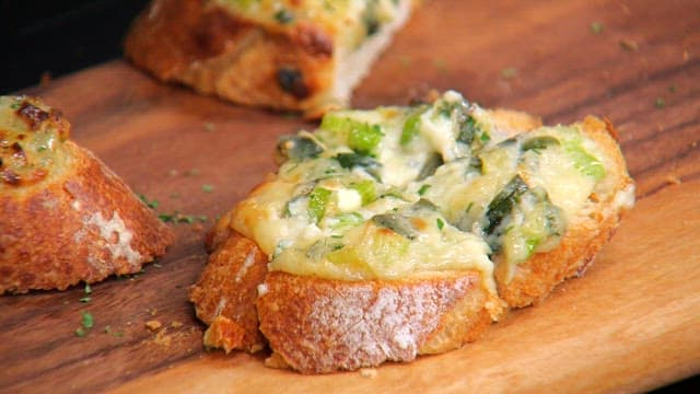 Crispy and appetizing baguette topped with green onions on a wooden cutting board