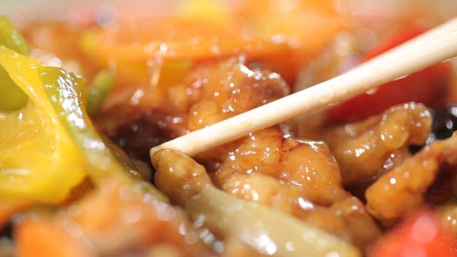 Piece of sweet and sour pork picked up with chopsticks