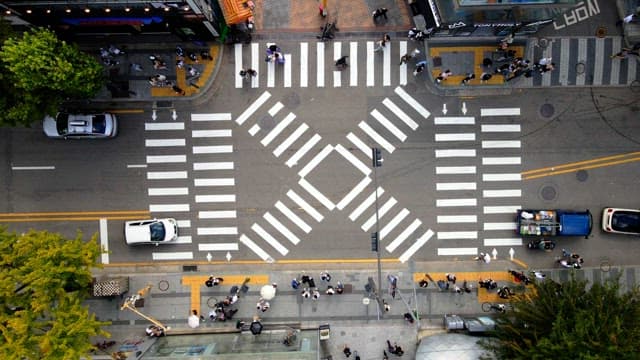 Busy city street crossing seen from above with pedestrians and cars