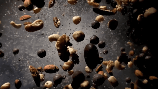 Various types of nuts bouncing with smoke on black background