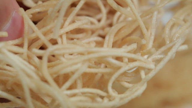 Hands touching crispy fried noodles
