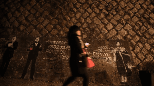 Passerby passes by graffiti depicting great Korean figures