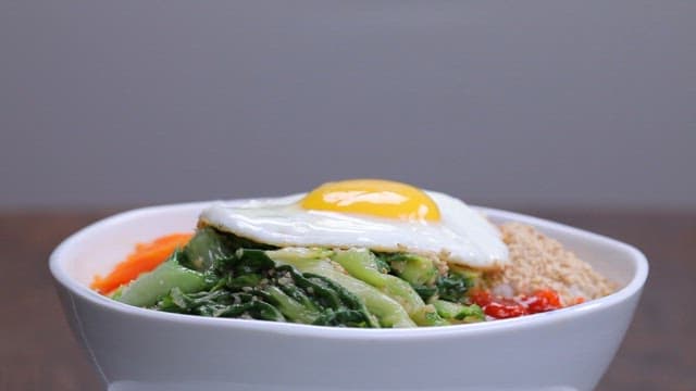 Bowl of bibimbap with fresh vegetables and fried egg