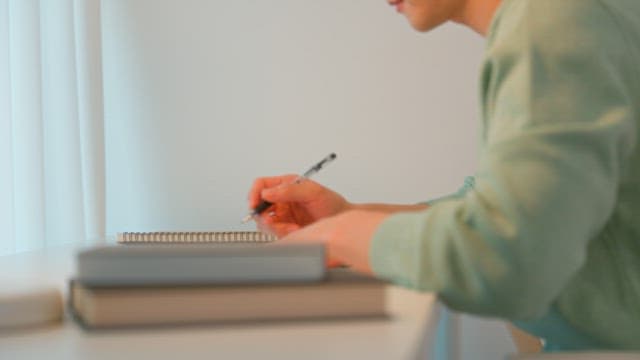 Man writing at a desk in a calmly lit room