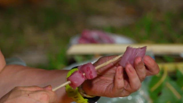 Skewering fresh tuna pieces on a stick