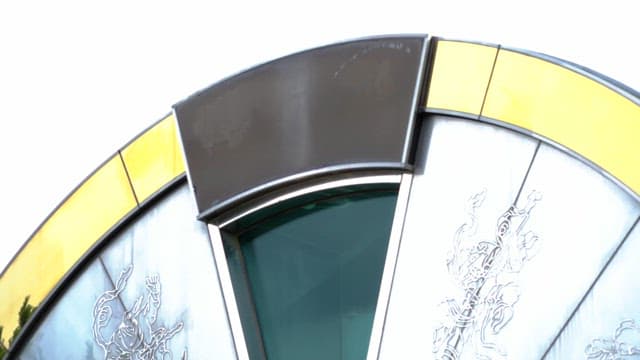 Passing tourists reflected in a giant hourglass