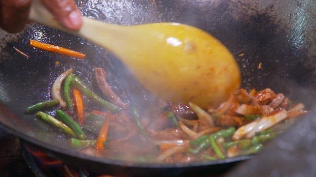 Stir-frying vegetables and beef in a wok