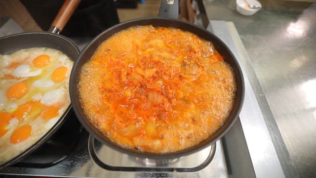 Fried eggs and kimchi stew cooked on a gas stove in the kitchen