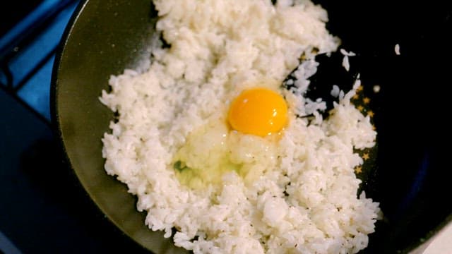Egg being mixed with rice in a pan