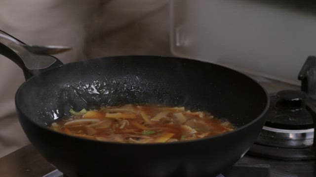 Egg mixture added to dishes sizzling in a frying pan