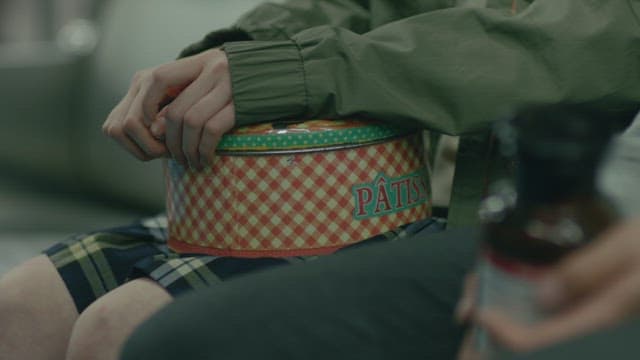 Hands holding a round tin case and a bottle of chemicals