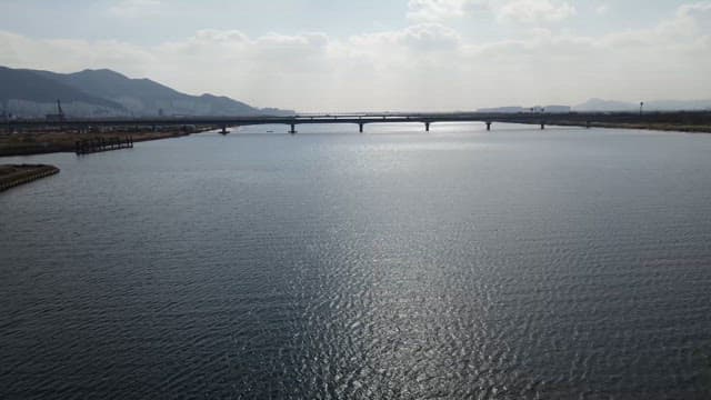 Wide river with a bridge and mountains