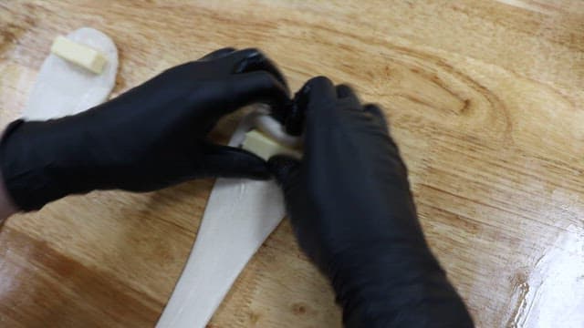 Scene of putting salted butter rolls into dough and rolling it