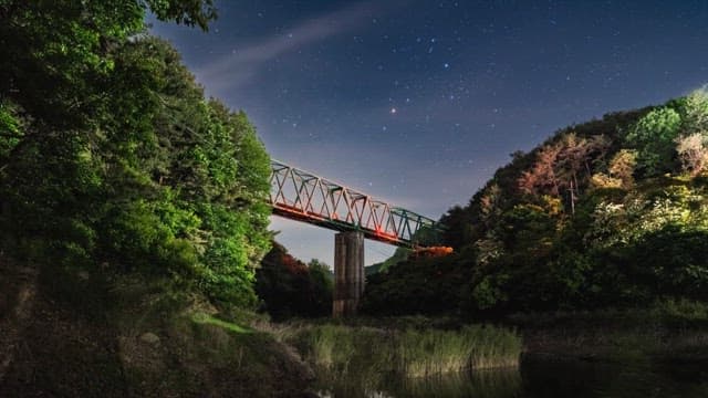 Night sky visible over the mountains and bridge