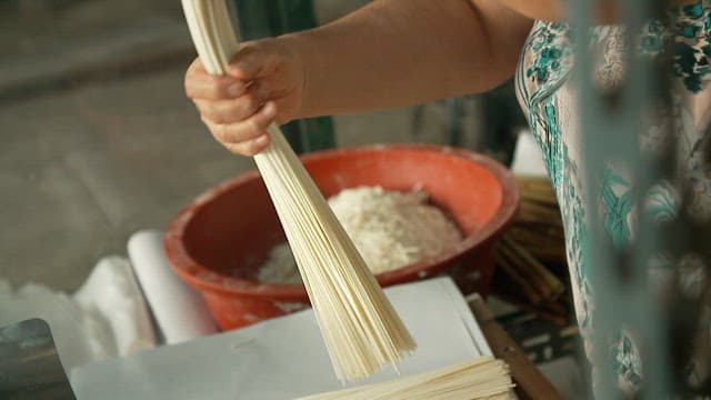 Hands handling handmade noodles made from wheat flour
