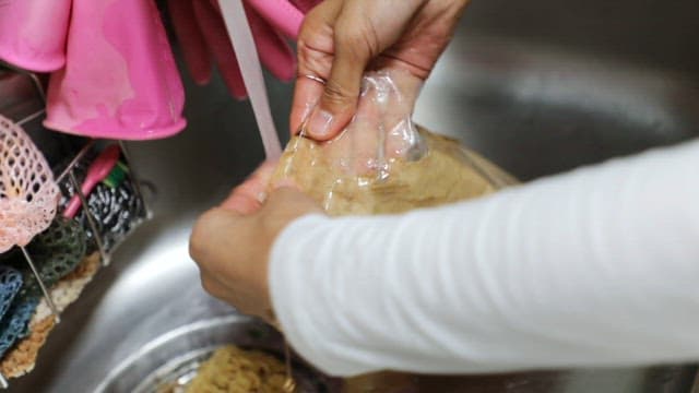 Someone washing a package in a kitchen sink
