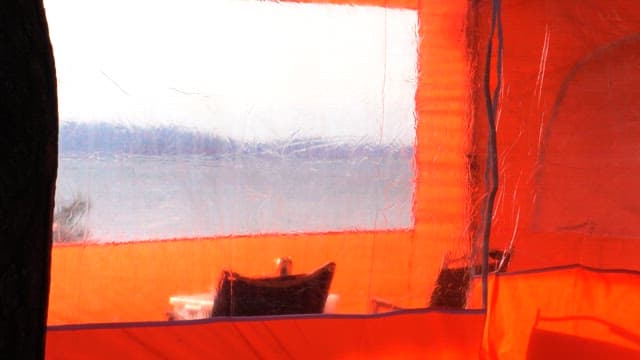 Transparent orange tent with empty chairs inside