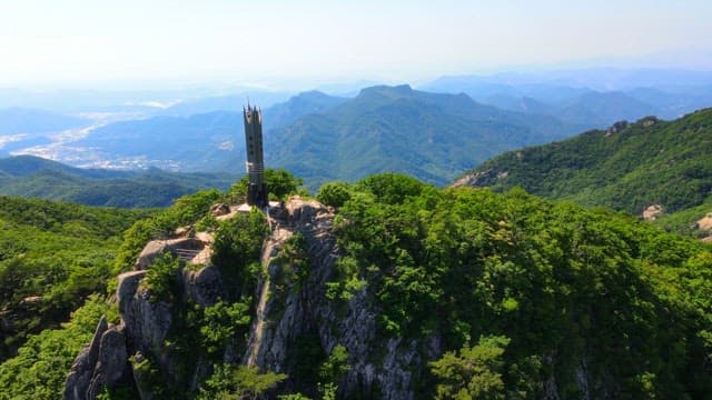 Mountain landscape with a tower commemorating the summit under a clear sky