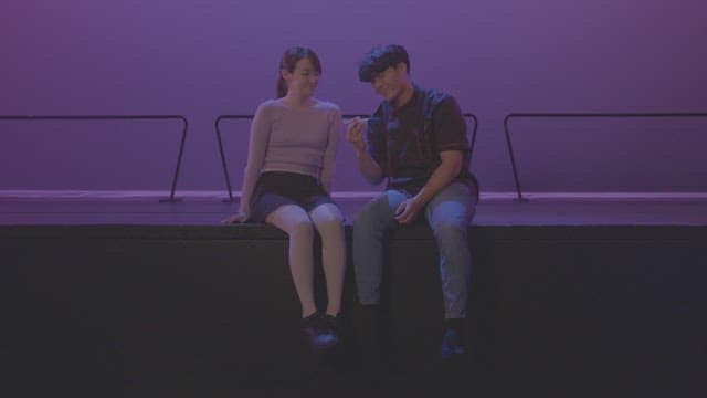 Couple sitting on a stage under purple lighting