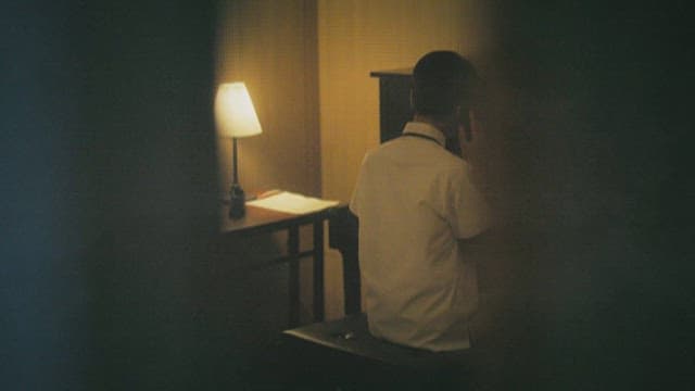 Back View of a Student Sitting in Front of a Piano with Sheet Music