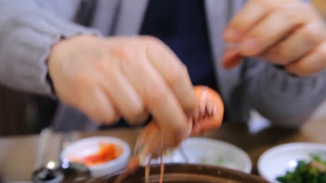 Peeling shrimp at a dining table