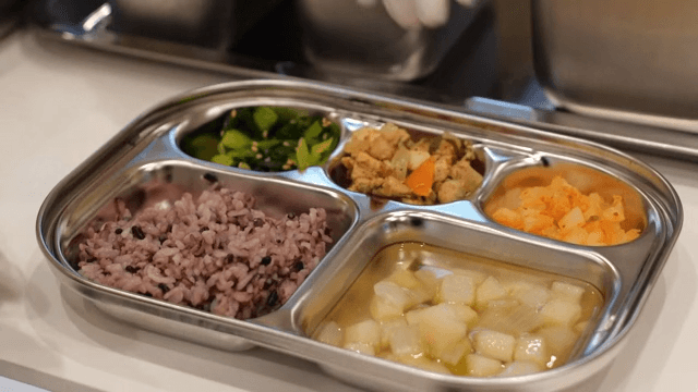 Rice, soup, and various side dishes served on a metal plate