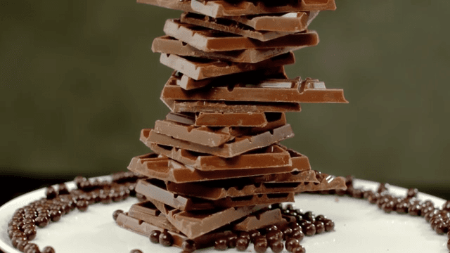 Chocolate balls falling onto a tower of chocolate pieces piled on a plate
