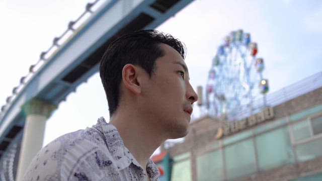 Man drinking water near a ferris wheel