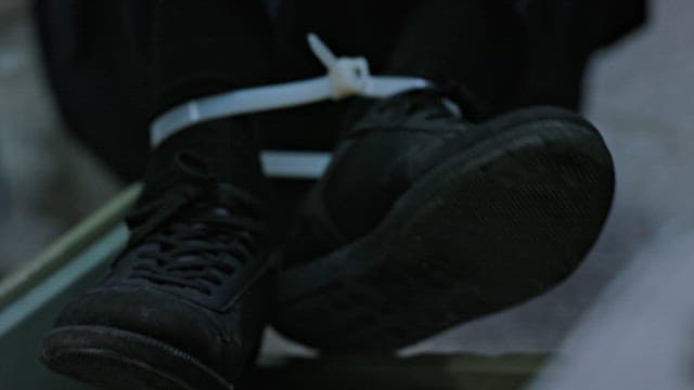 Person Struggling to Loosen the Cable Ties Binding his Feet