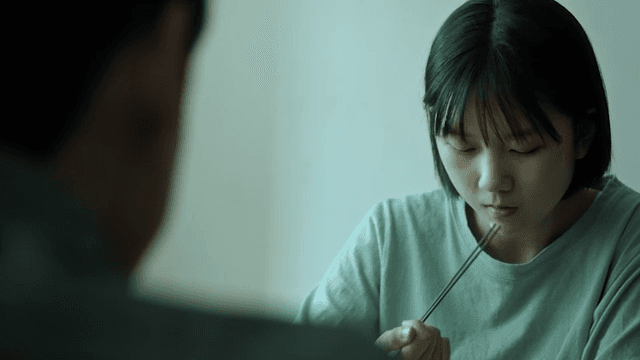 Girl eating at the table with a depressed expression