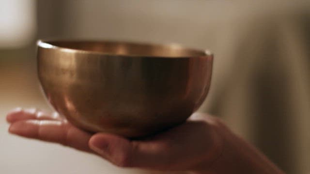 Rubbing singing bowl on the hands with a stick