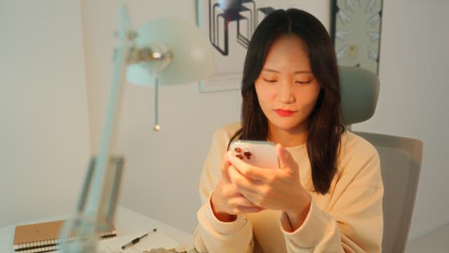 Woman using a smartphone at a desk in a calmly lit room