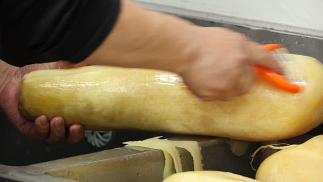 Peeling a Large Radish with a Peeler in the Kitchen