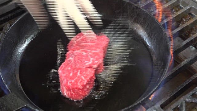 Sizzling beef steak on a flaming grill pan